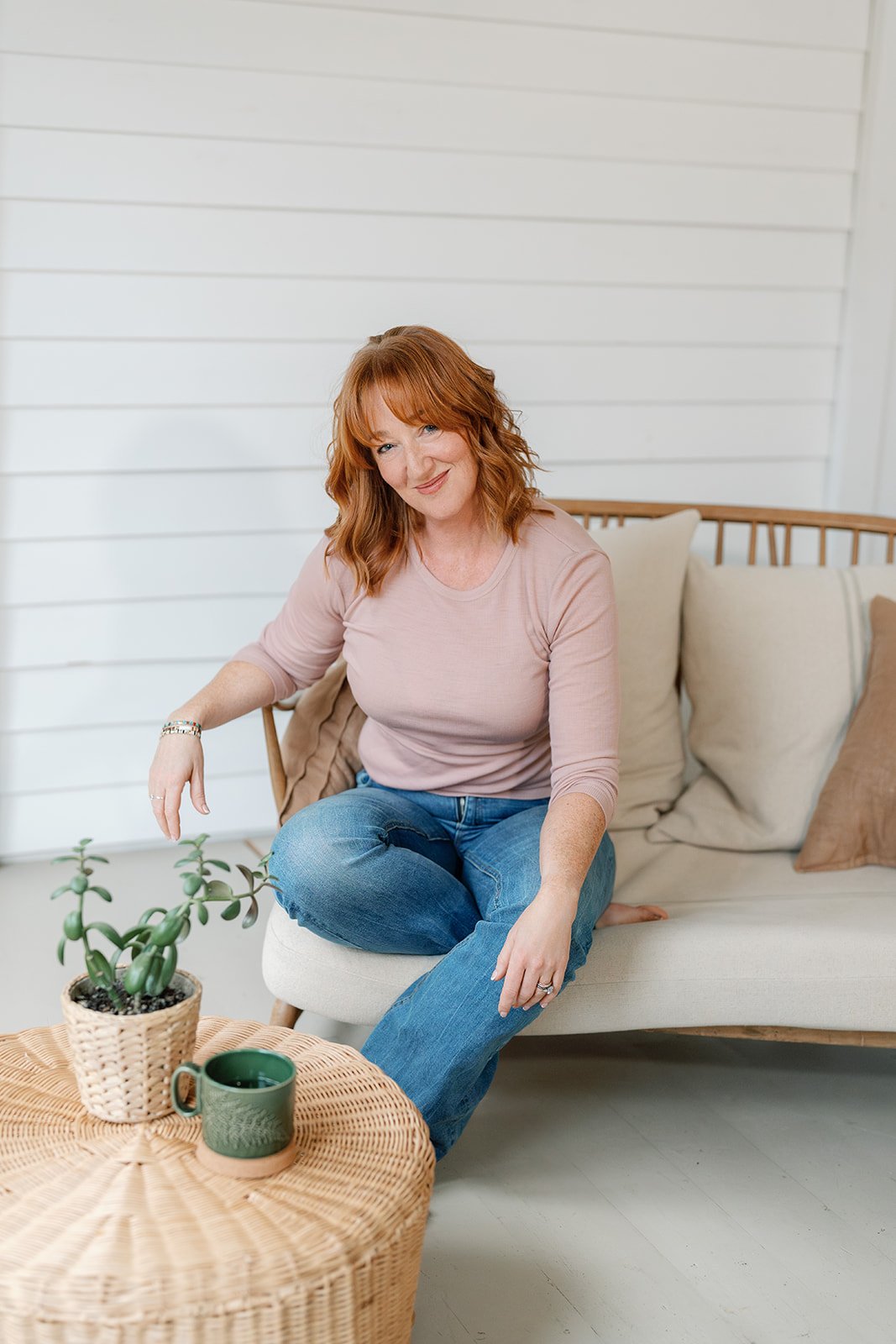 Amanda Alexander sat on a sofa wearing a blush pink jumper